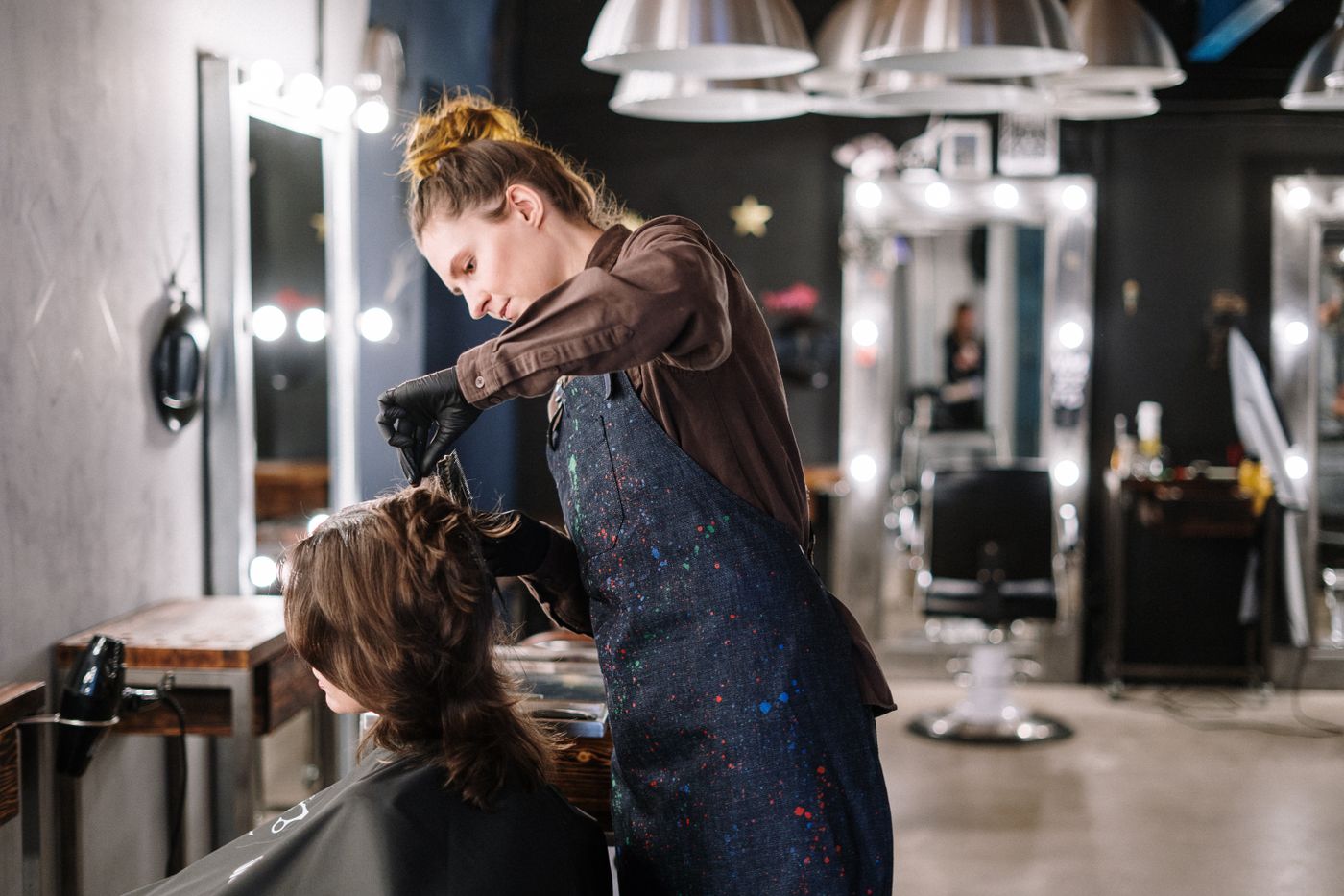 A stylist applying colour to a client's hair in a salon